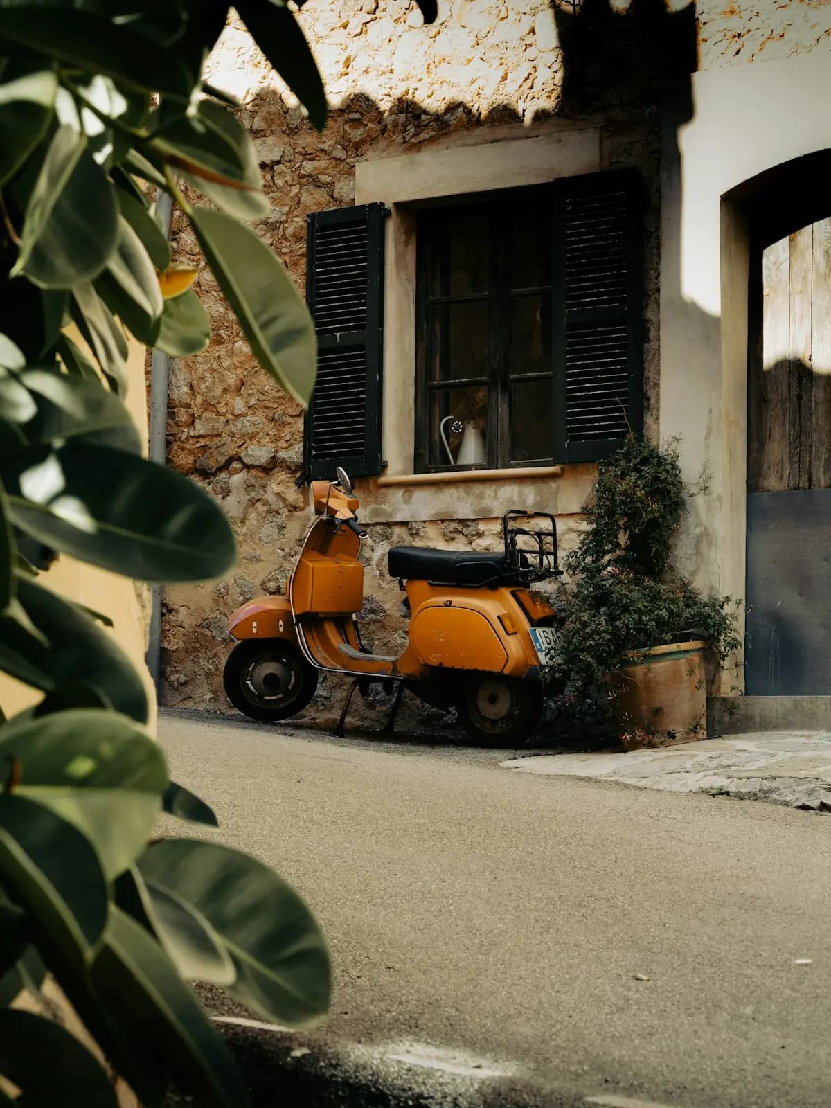 Scooter naranja aparcado frente a una fachada mediterránea